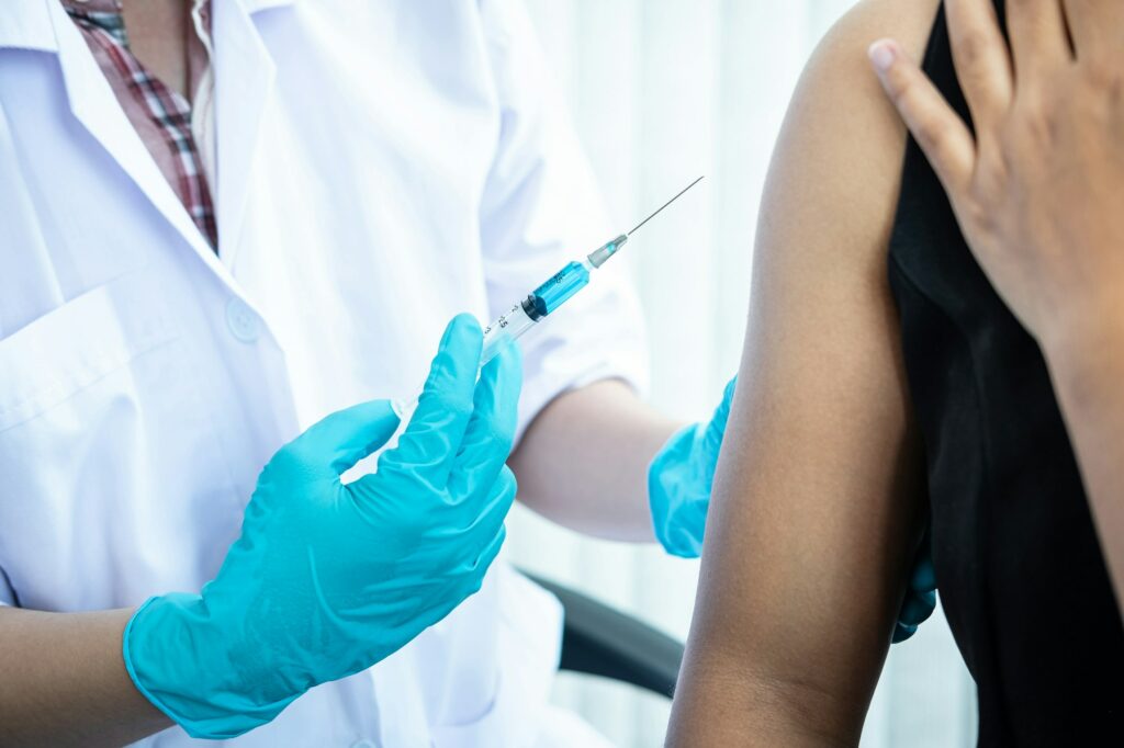 Doctor making a vaccination into patient with needle getting immune vaccine at arm for flu shot